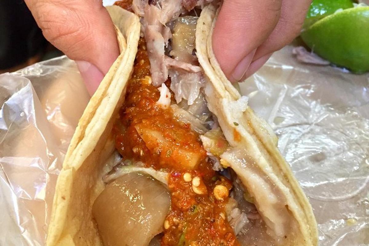 osoba držící taco s masem a omáčkou