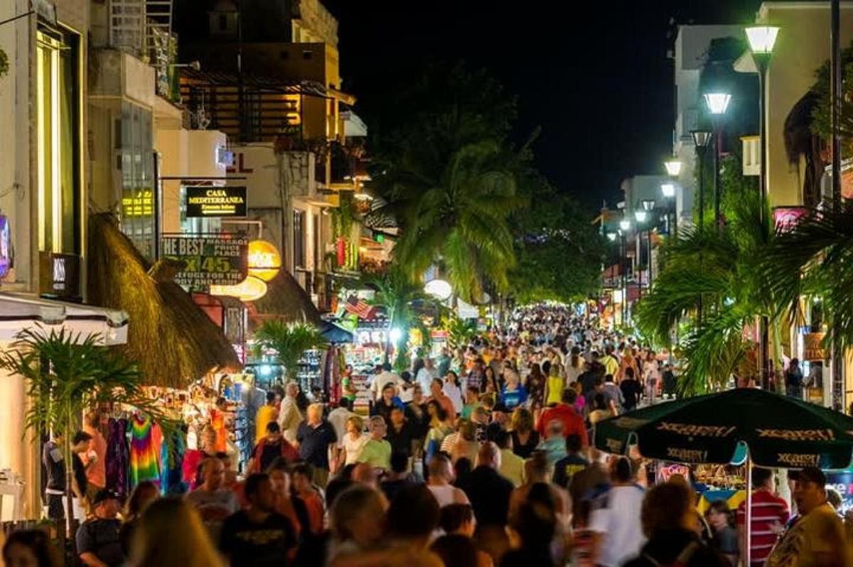 a crowd of people walking down a street at night