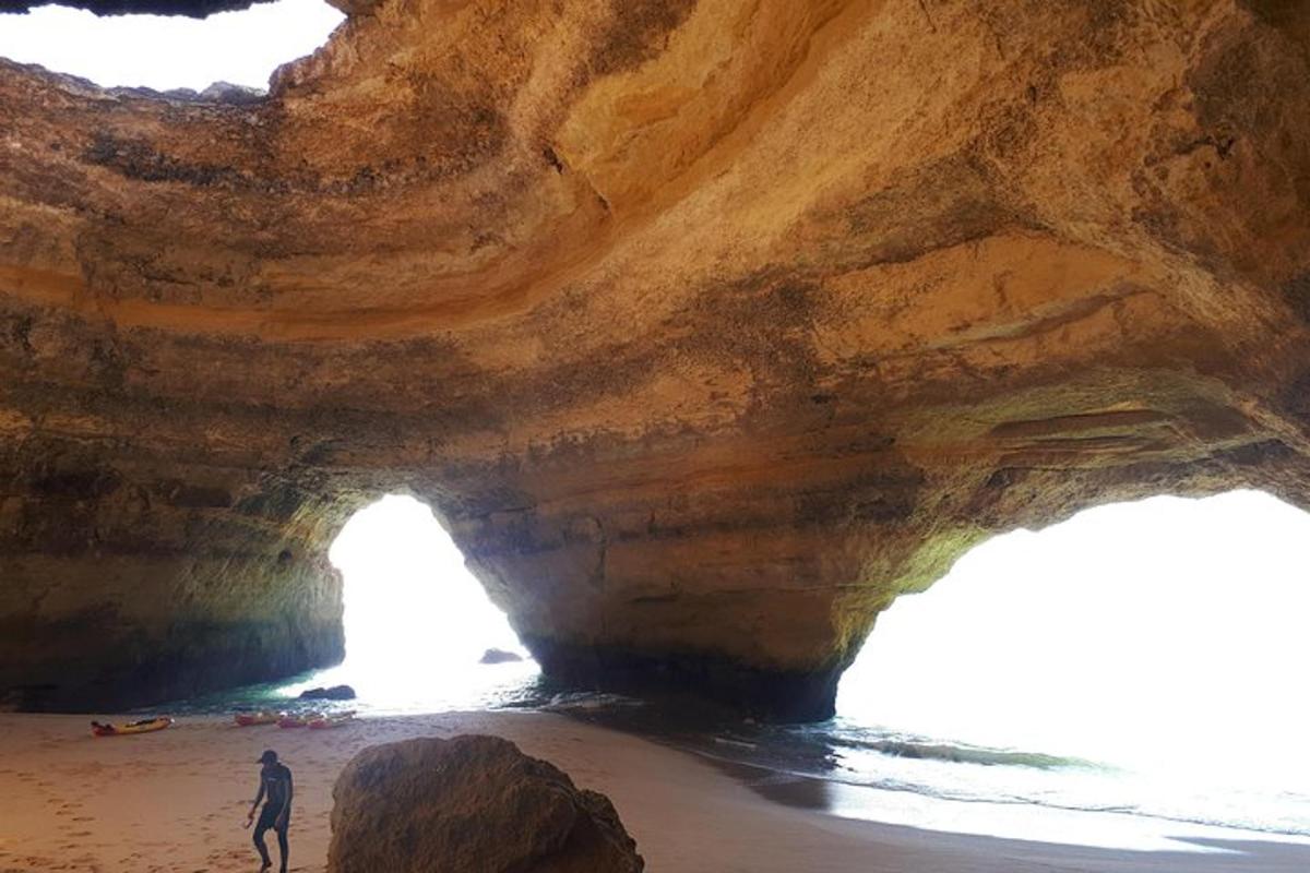 seorang lelaki berdiri di hadapan sebuah gua di pantai