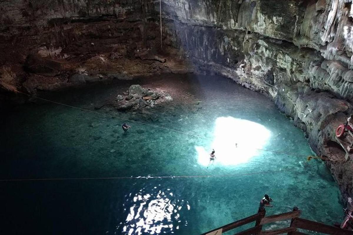 uma caverna com pessoas nadando em uma piscina de água
