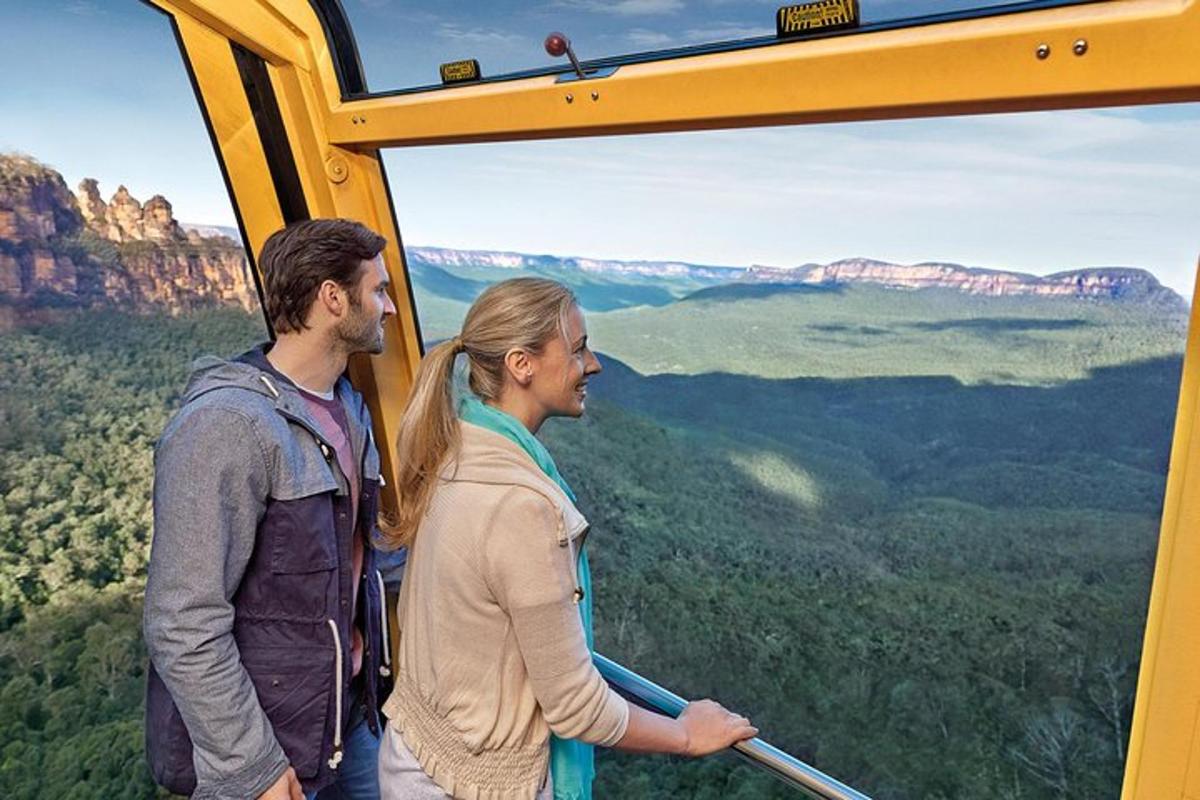 a man and a woman standing inside of a helicopter in the blue mountains