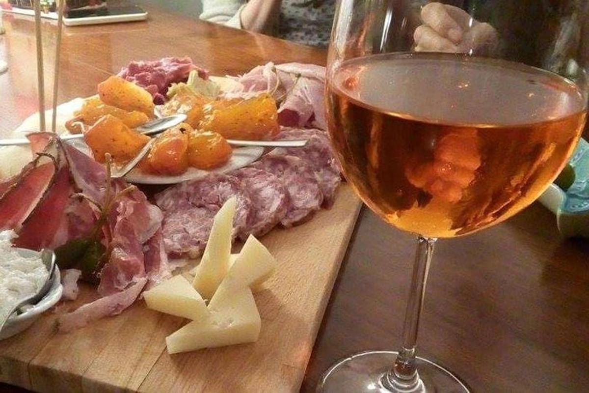 ein Glas Wein neben einem Teller mit Fleisch und Käse