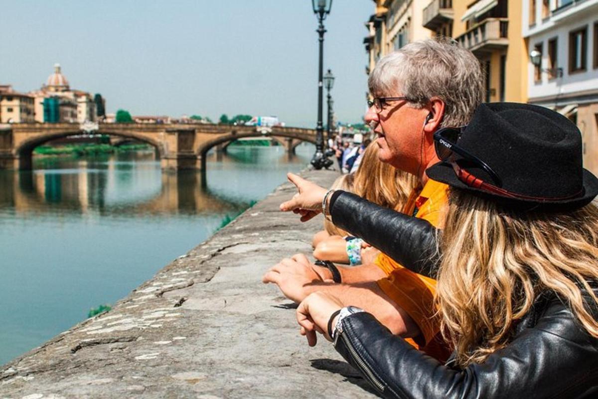 two people sitting on a wall next to a river