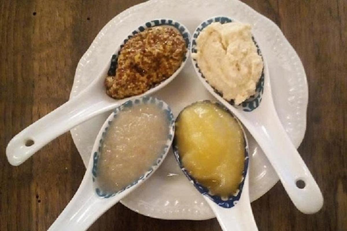 een wit bord met vier lepels op een tafel