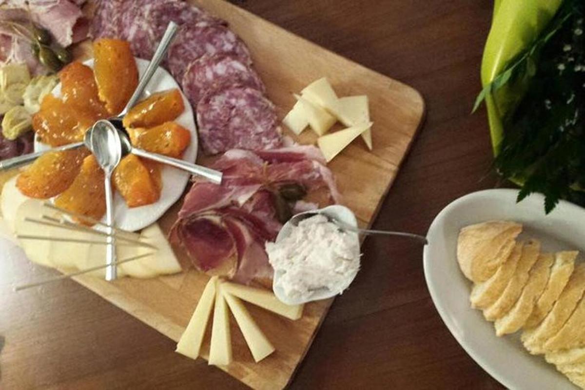 uma mesa de madeira com um prato de queijo e outras comidas