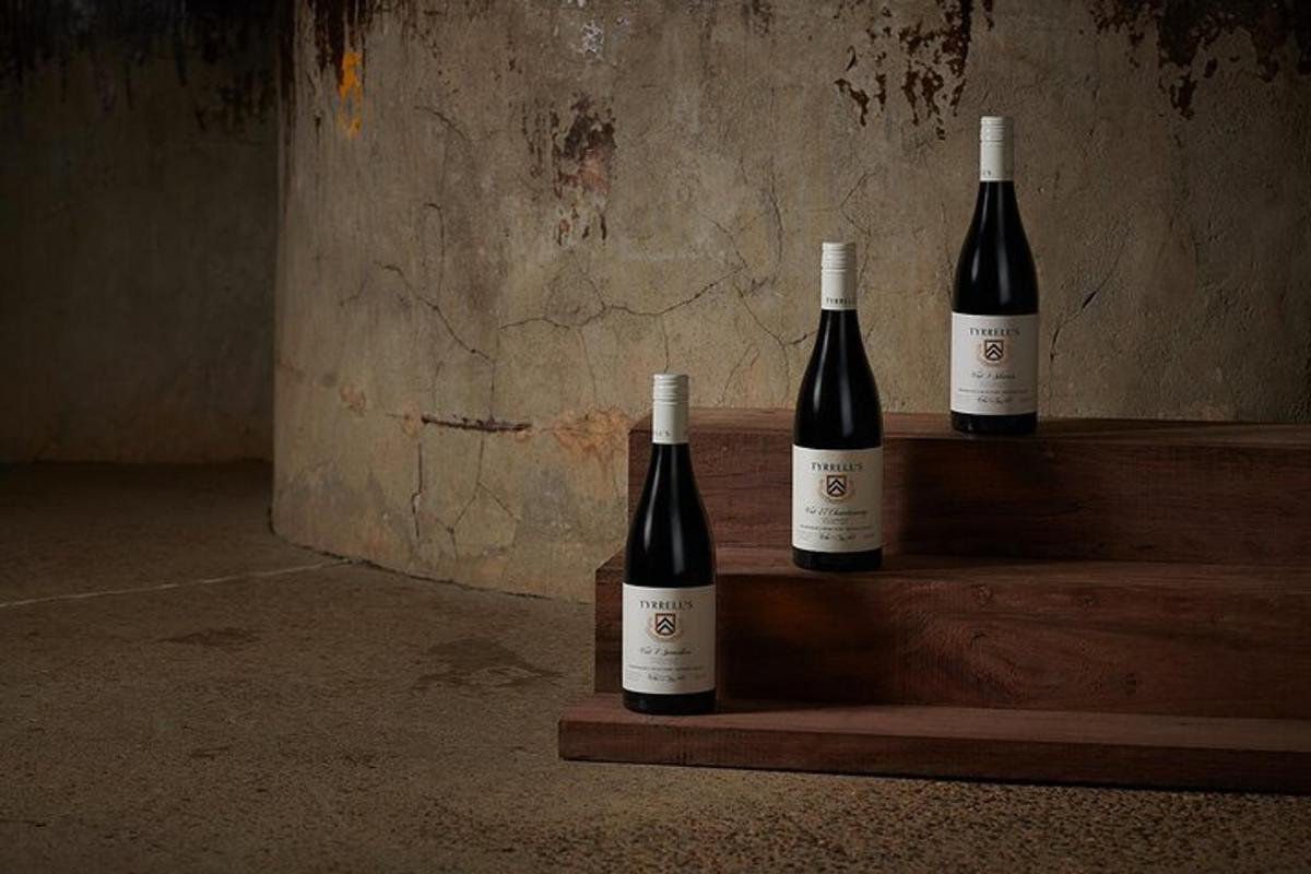 three bottles of wine sitting on a wooden shelf
