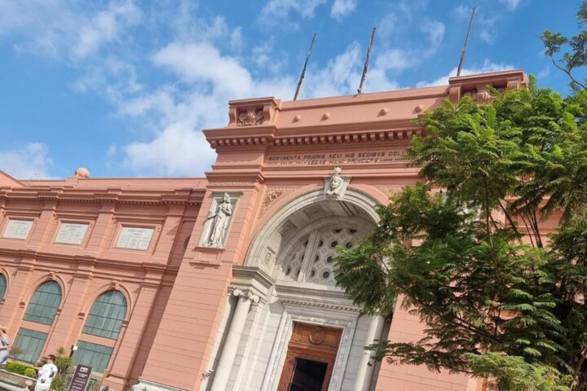 un edificio rosa con un arco davanti a un albero