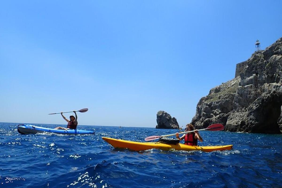 tre persone in kayak in acqua vicino a una scogliera
