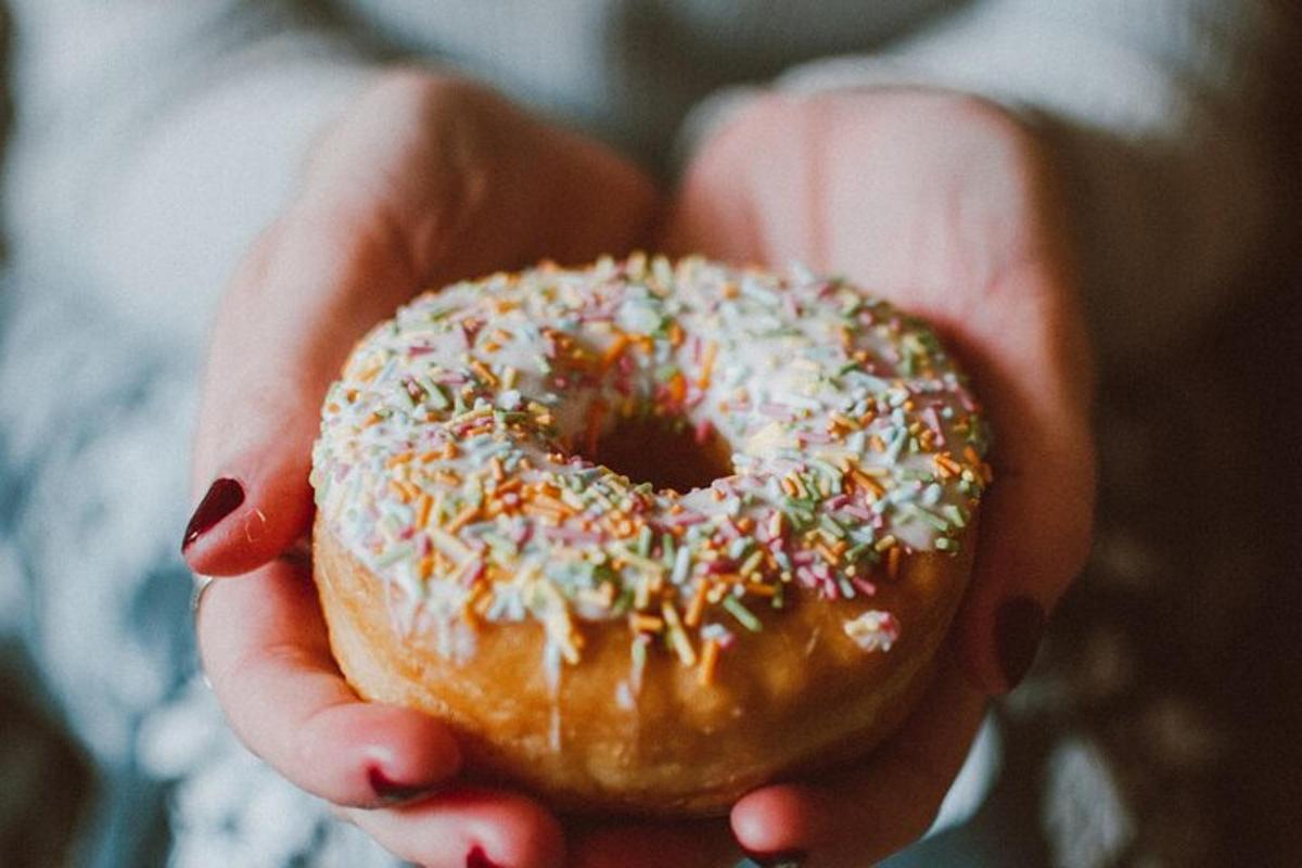 una persona che tiene in mano una ciambella con granella