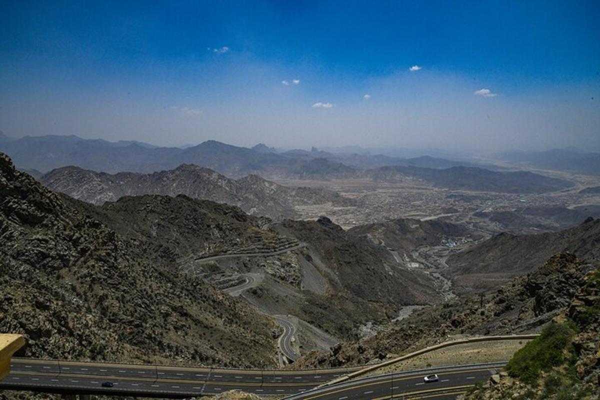 a view of a mountain with a road and mountains