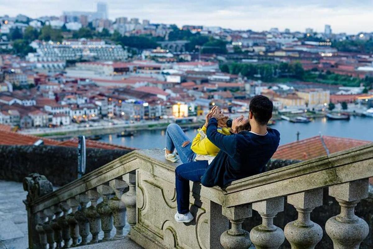 Un hombre sentado en una cornisa tomando una fotografía de una ciudad.