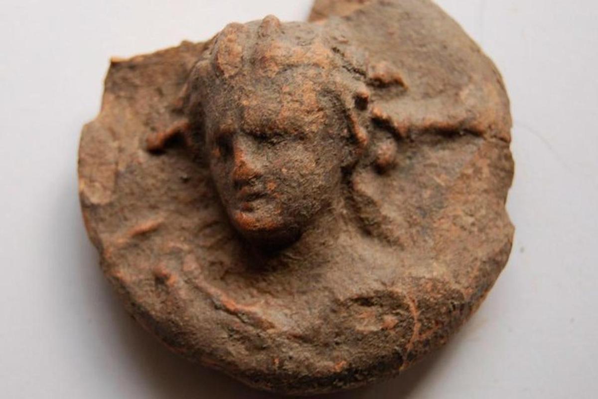 un artefact din bronz al unei fețe pe un perete
