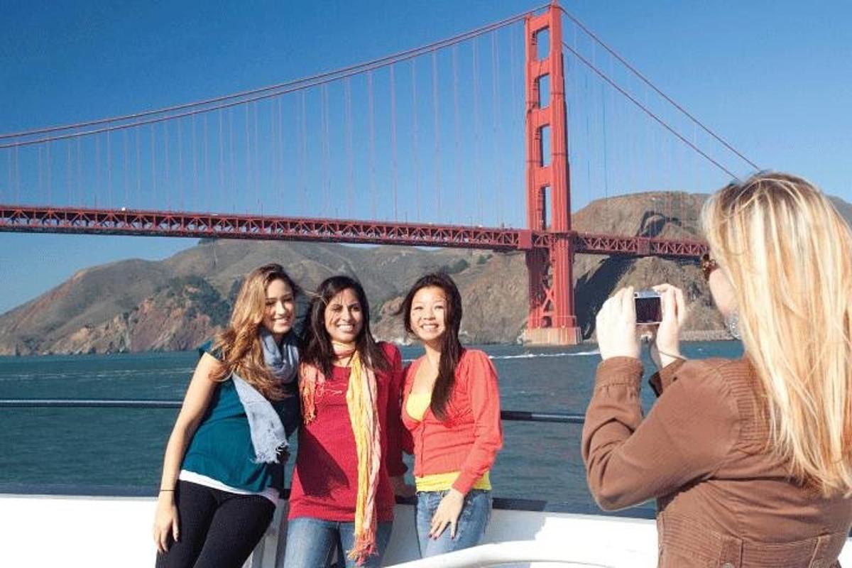 a group of women standing on a boat in front of the golden gate bridge