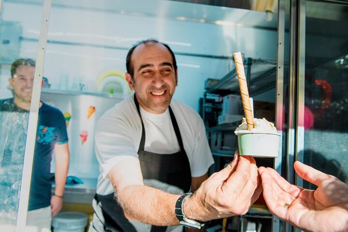 a man in a kitchen giving a person a piece of food