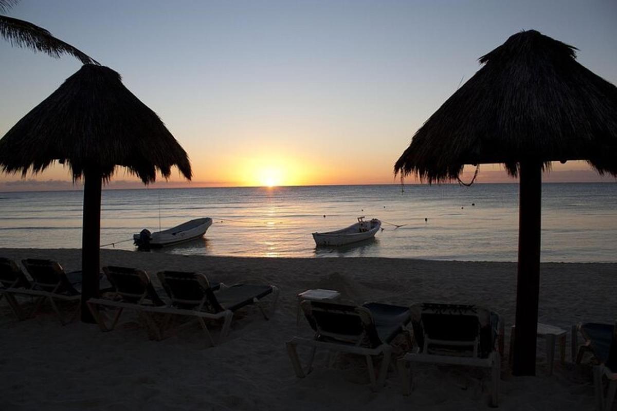 una spiaggia con sedie e ombrelloni e una barca in acqua