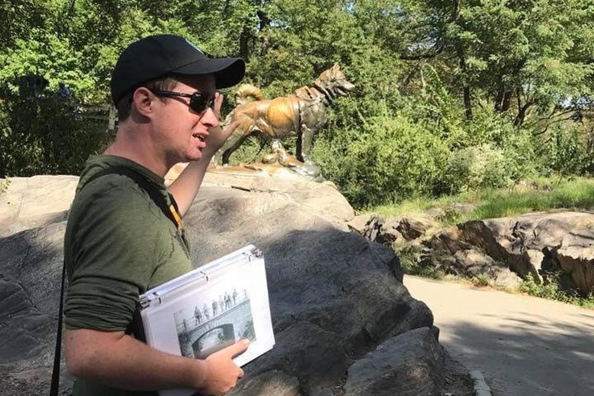 a man holding a sign in front of a statue of a horse