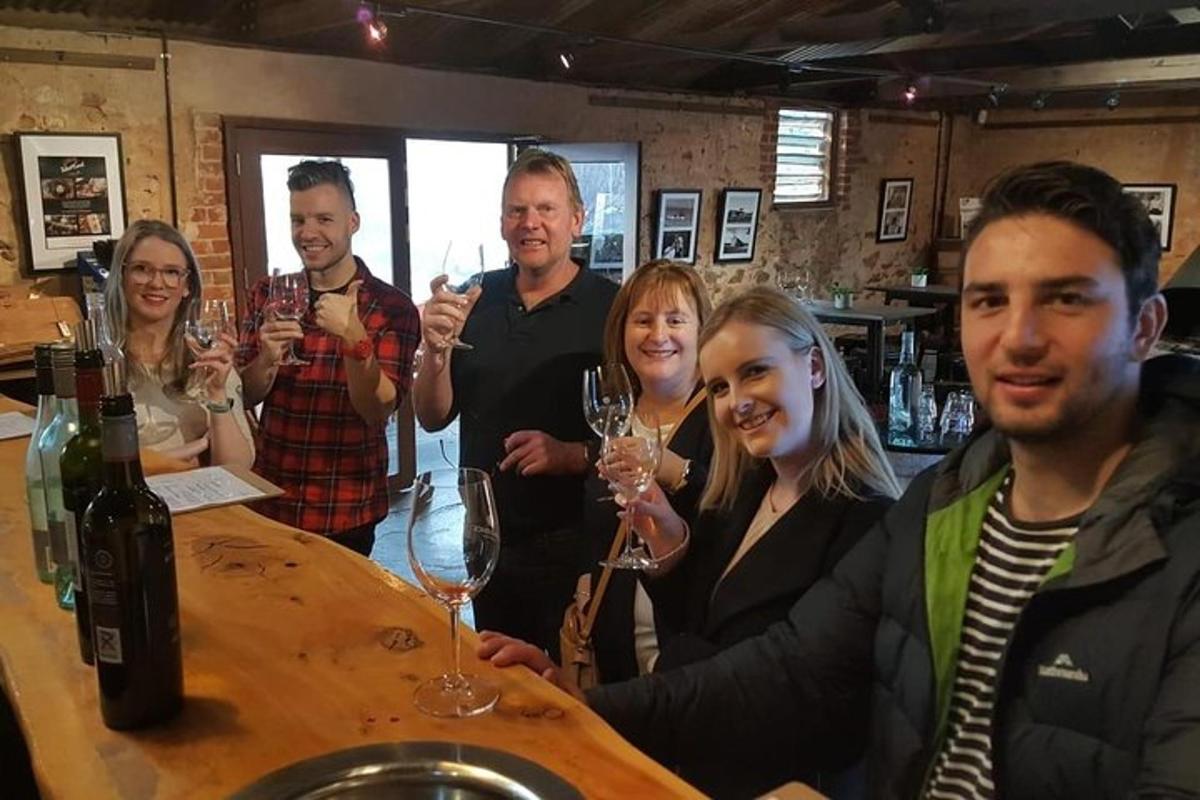 skupina lidí stojících kolem baru a držících sklenice na víno