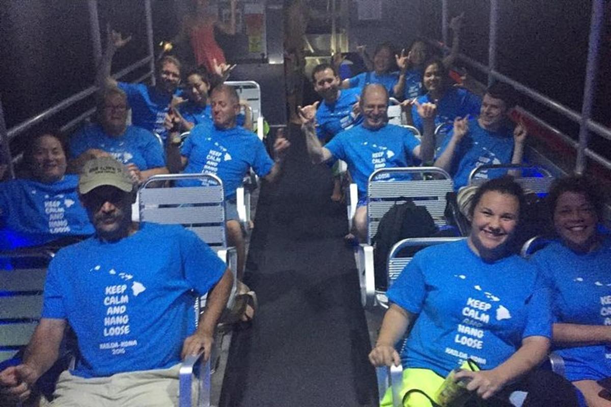 a group of people wearing blue shirts sitting in chairs