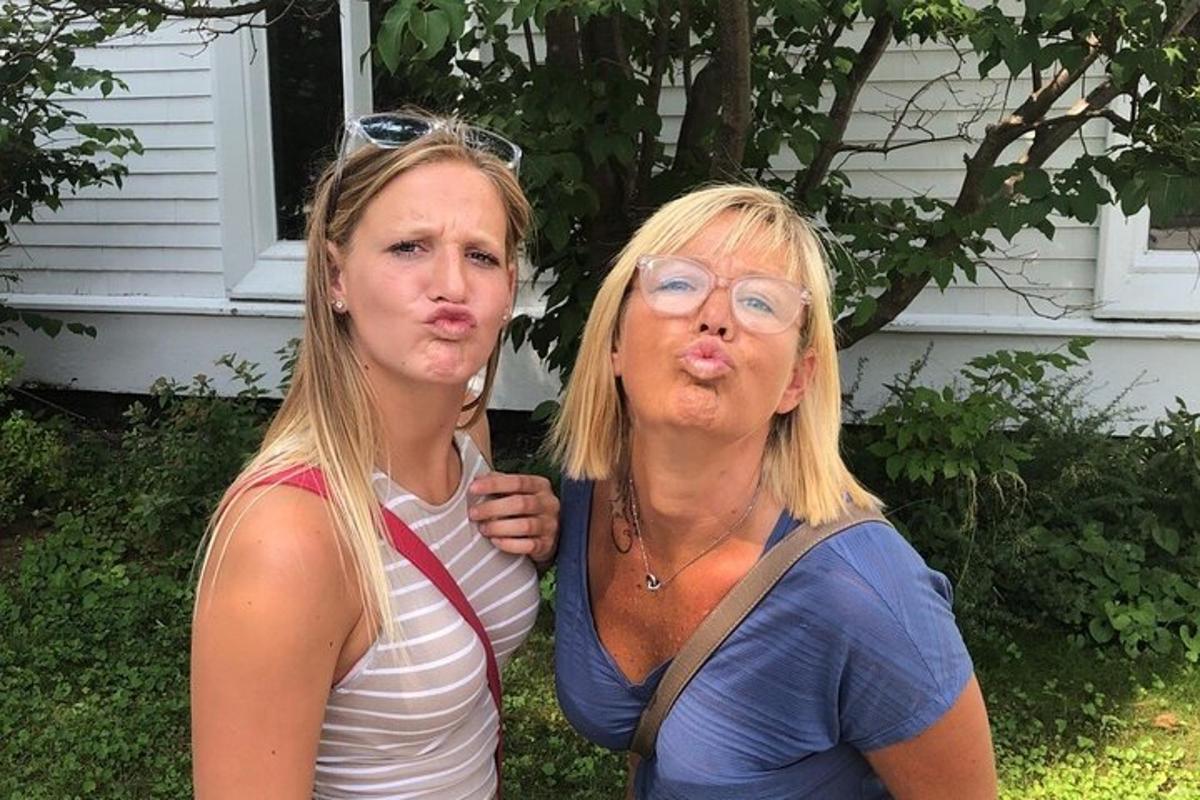 two women standing next to each other in front of a house