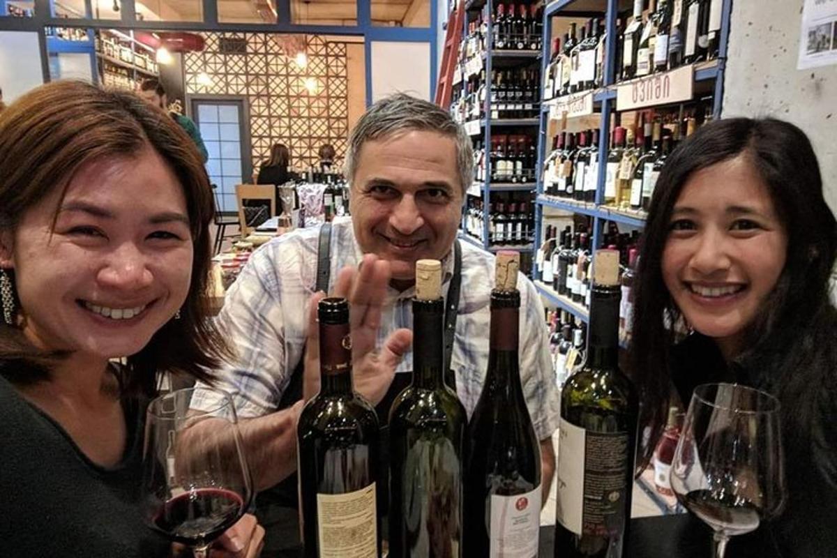 deux femmes et un homme tenant des bouteilles de vin