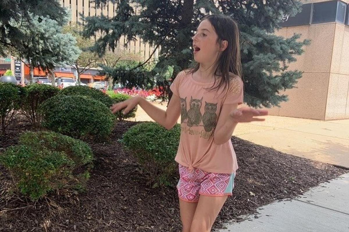 a young girl is standing on a sidewalk