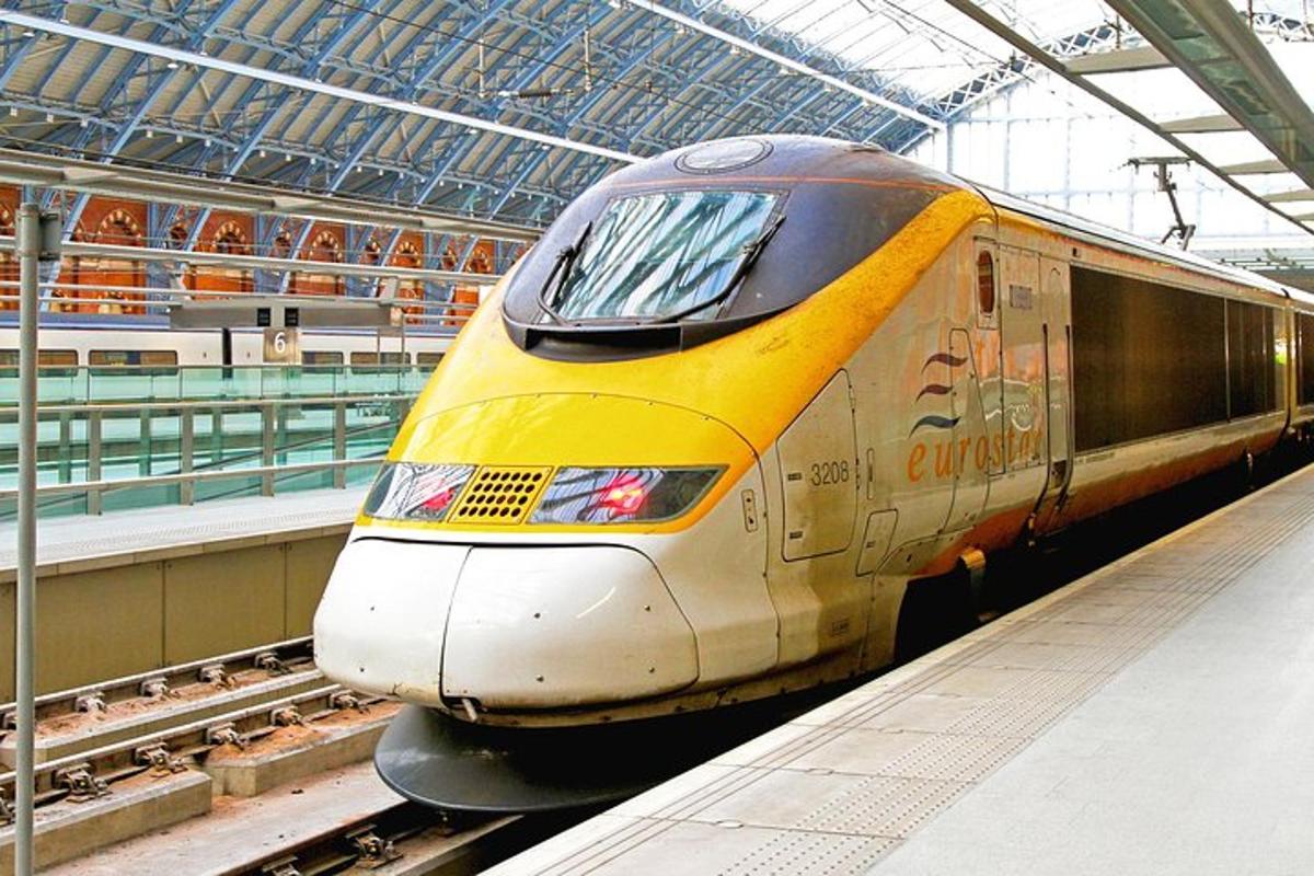 um trem amarelo e branco chegando em uma estação de trem