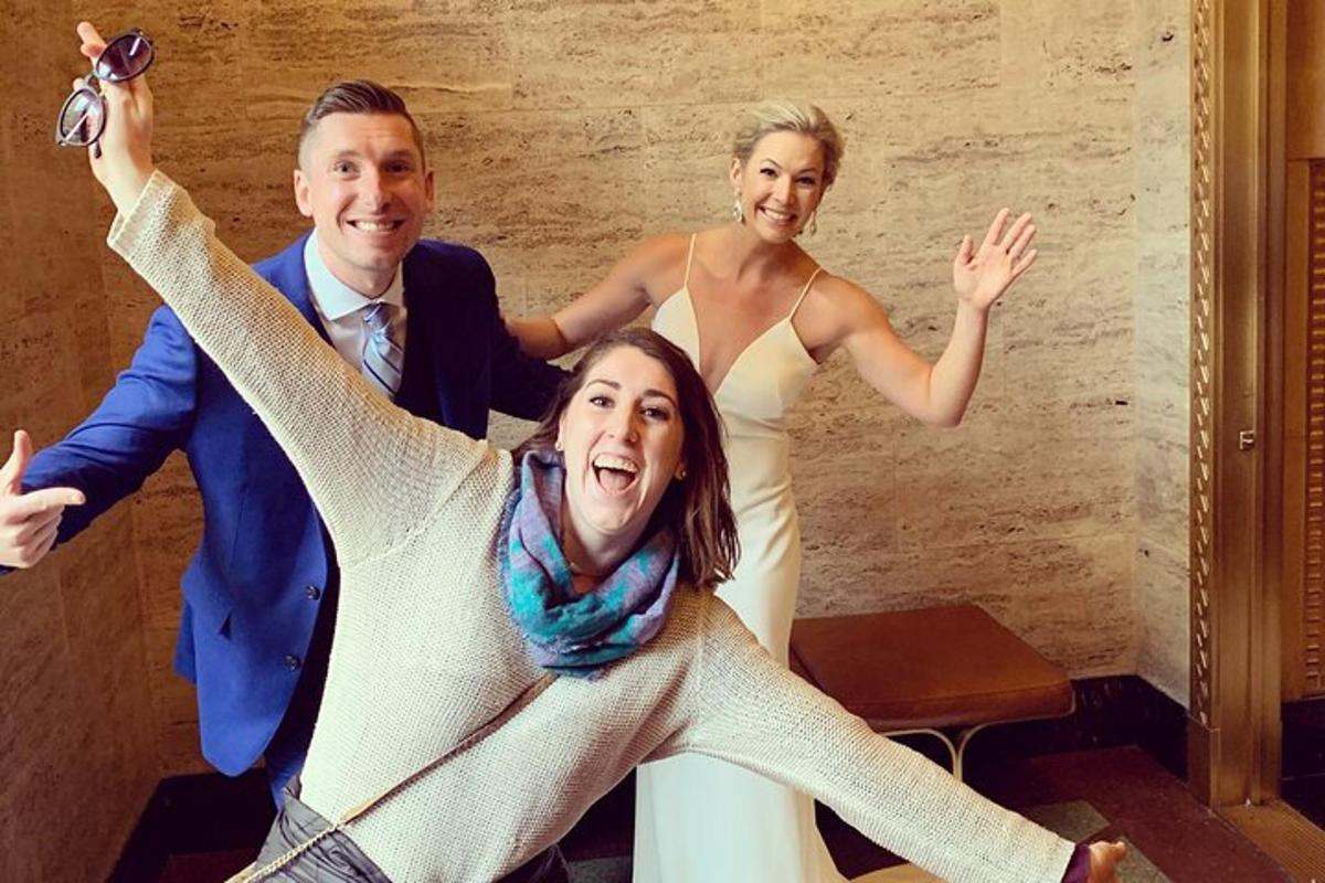 a bride and groom posing for a picture with their arms in the air