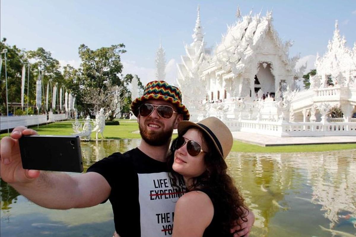 một người đàn ông và một người phụ nữ đang chụp ảnh trước một ngôi đền trắng