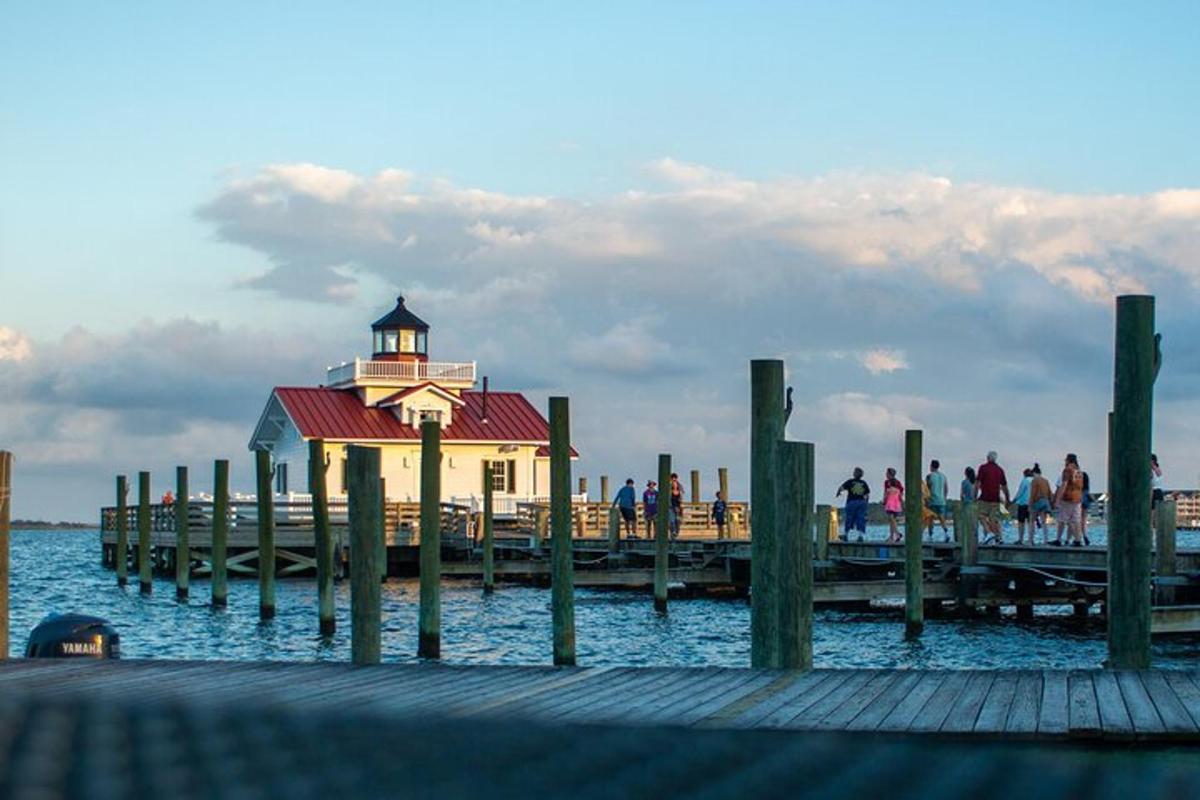 a group of people walking on a pier with a lighthouse