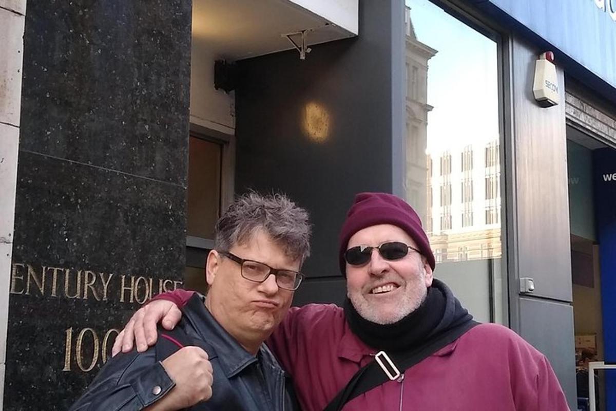 two men standing next to each other in front of a building
