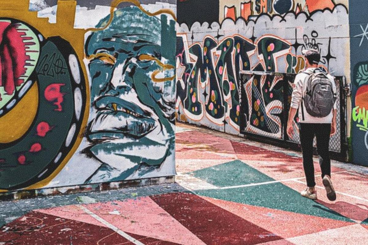 una persona che cammina davanti a un muro coperto di graffiti