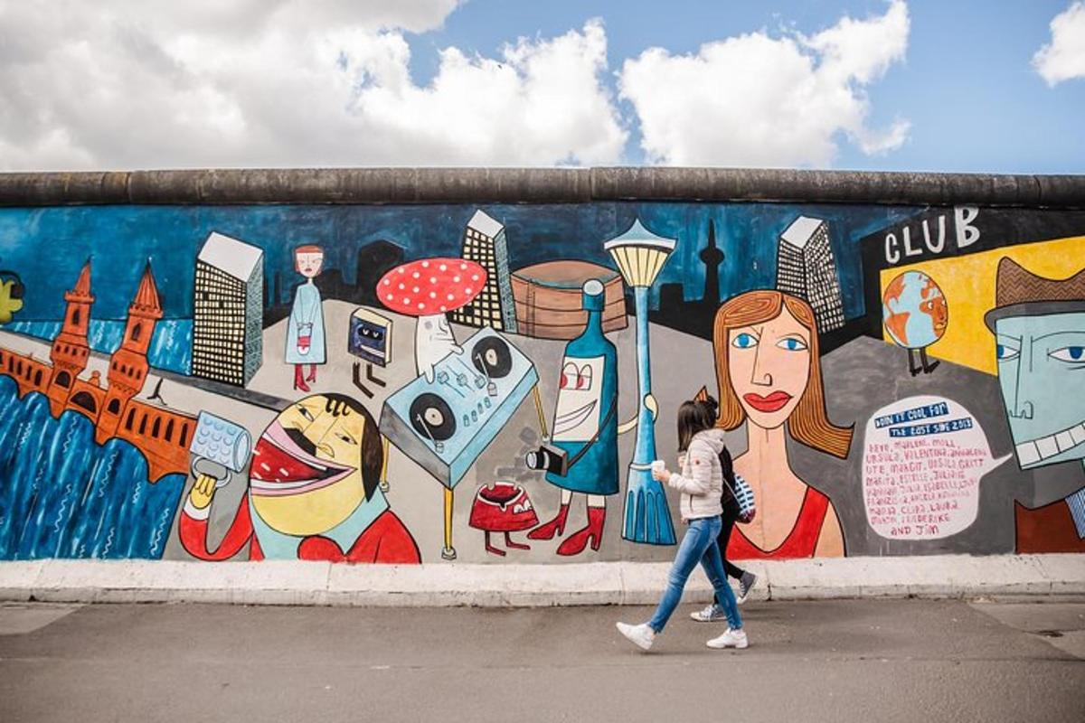 una donna che cammina davanti a un muro con un murale