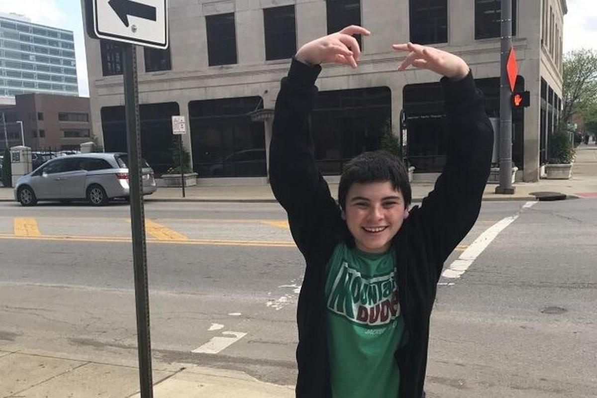 a young man is standing next to a street sign
