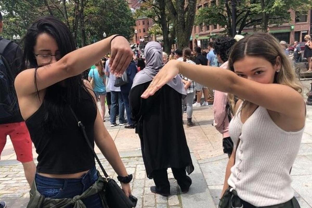 two young women standing on a street with their arms out