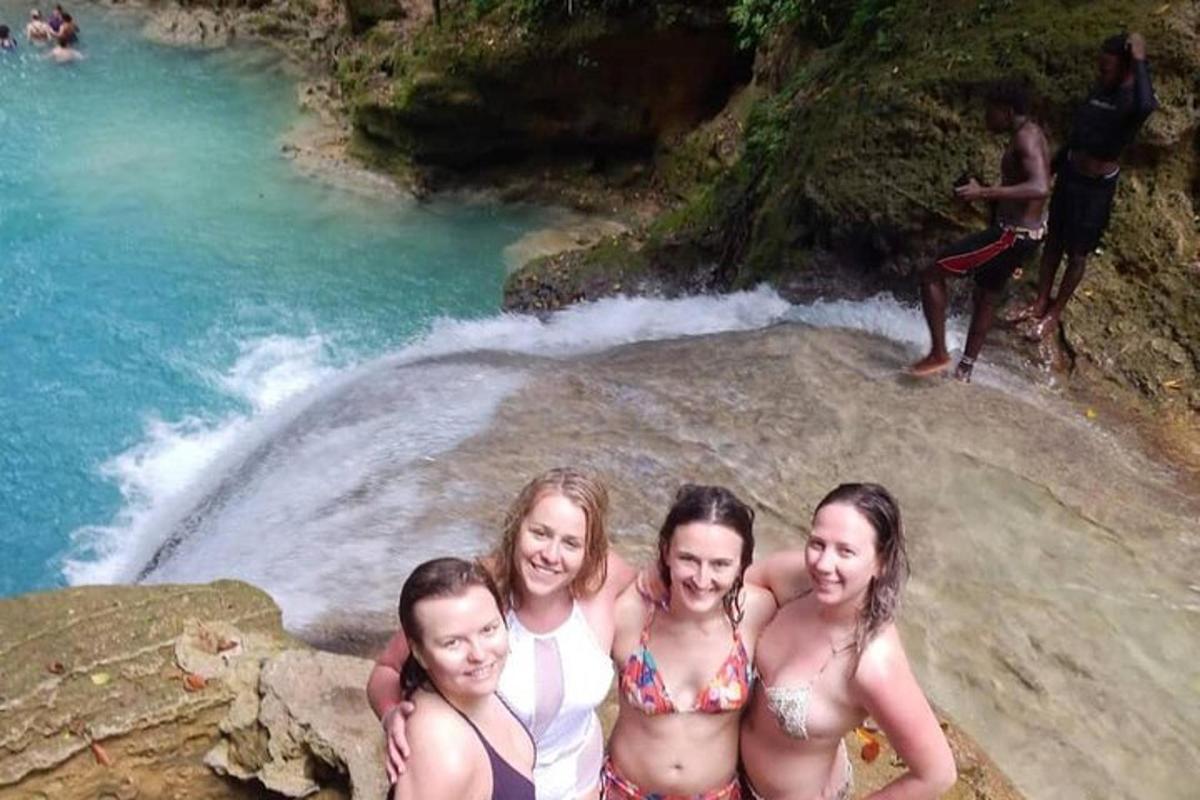 patru fete în costume de baie stând pe o stâncă într-un râu
