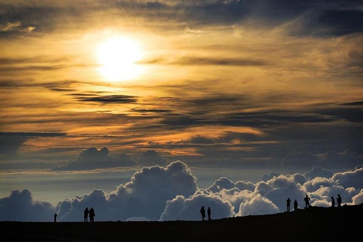 un gruppo di persone in piedi su una collina al tramonto