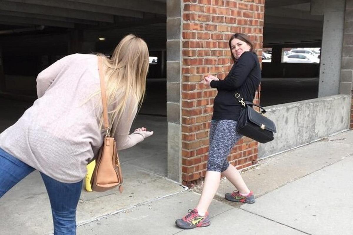 due donne in piedi su un marciapiede che guardano un muro di mattoni