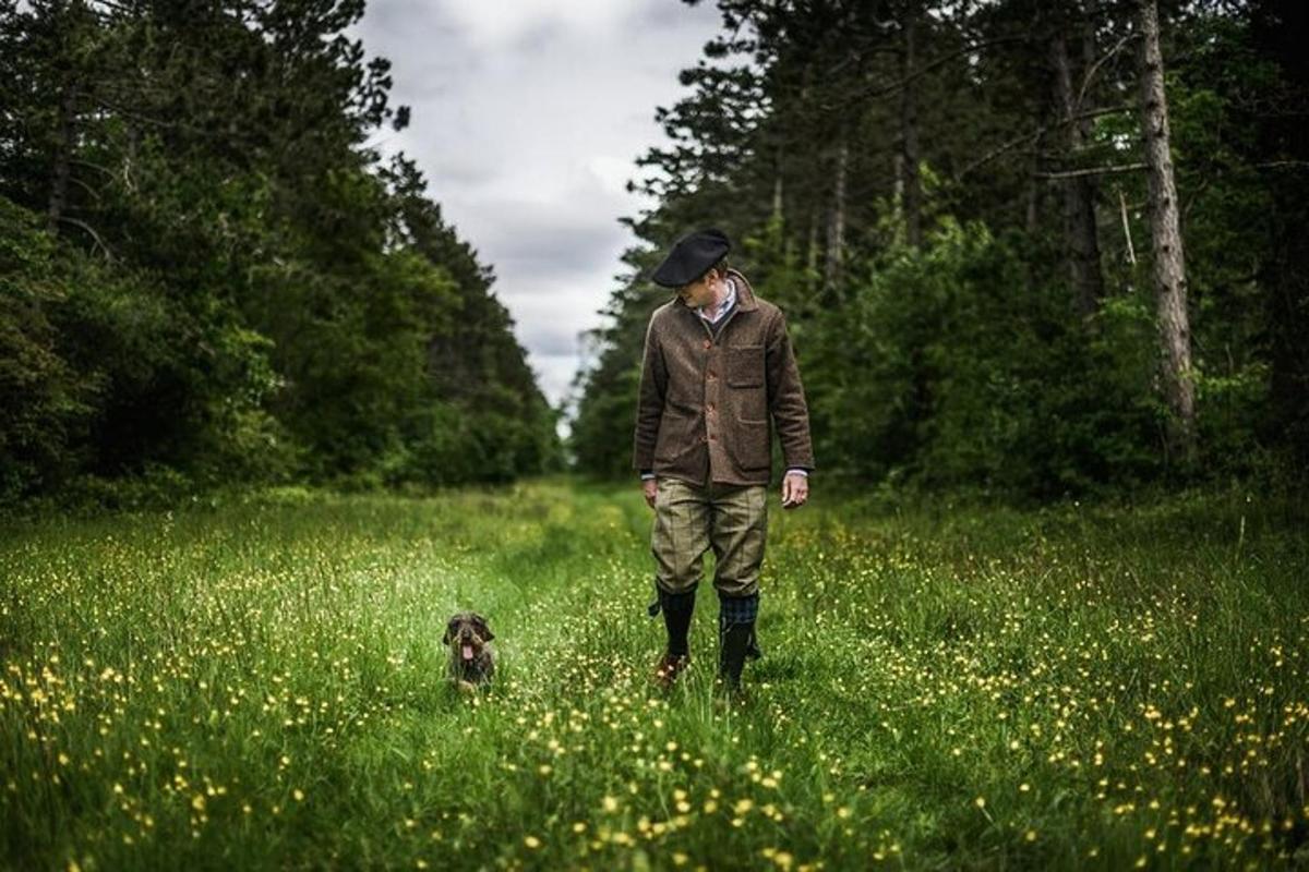 maður gengur með hund á túni