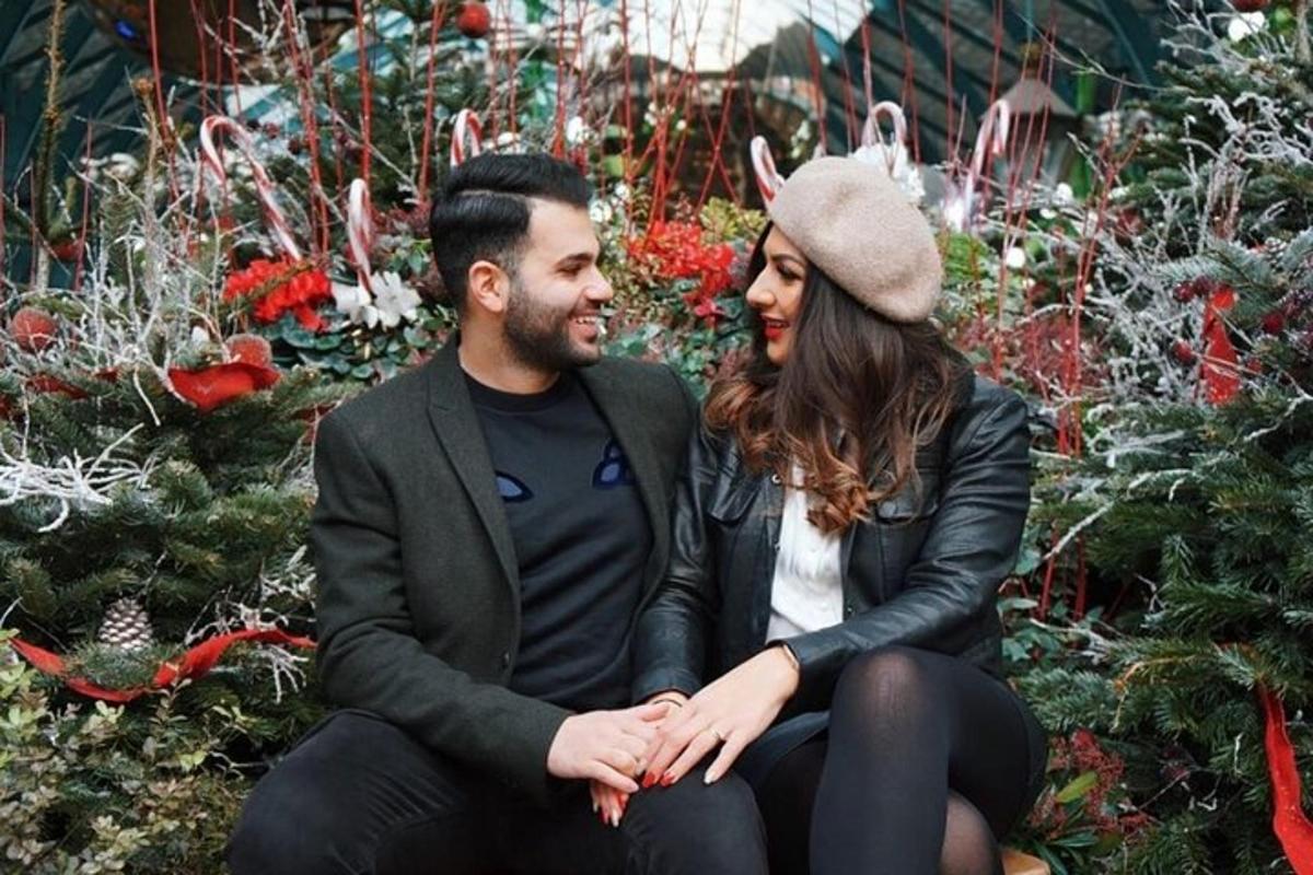 a man and a woman sitting in front of christmas trees