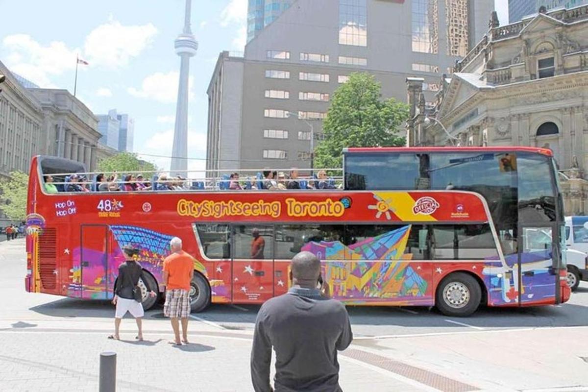 a red double decker bus with people standing in front of it