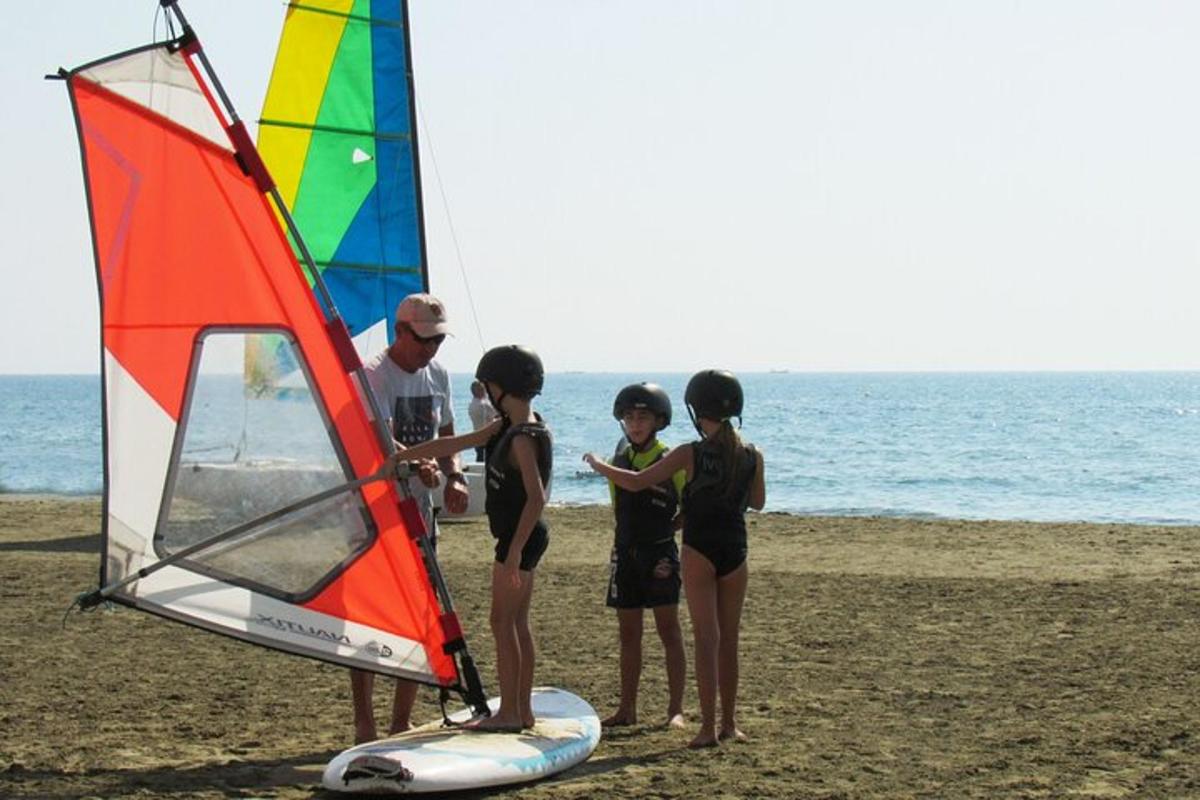 a group of people standing on the beach with a sail