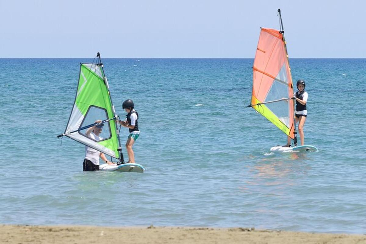 three people standing in the water with windsurfing