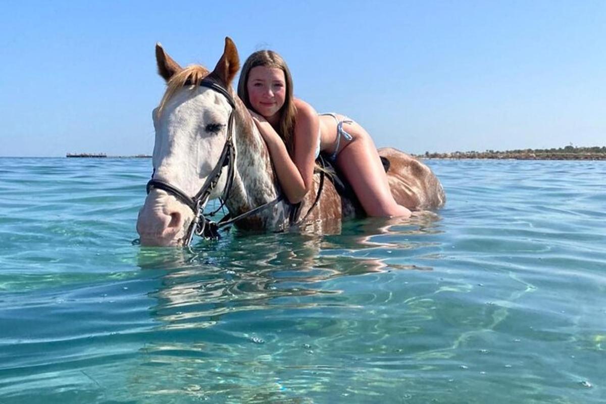 žena jedoucí na koni ve vodě