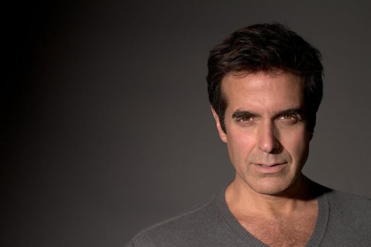 a man in a gray shirt is looking at the camera