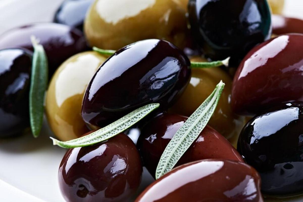 a pile of olives with green leaves on top