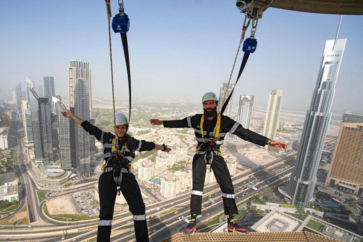 two people are zip lining on the top of a skyscraper