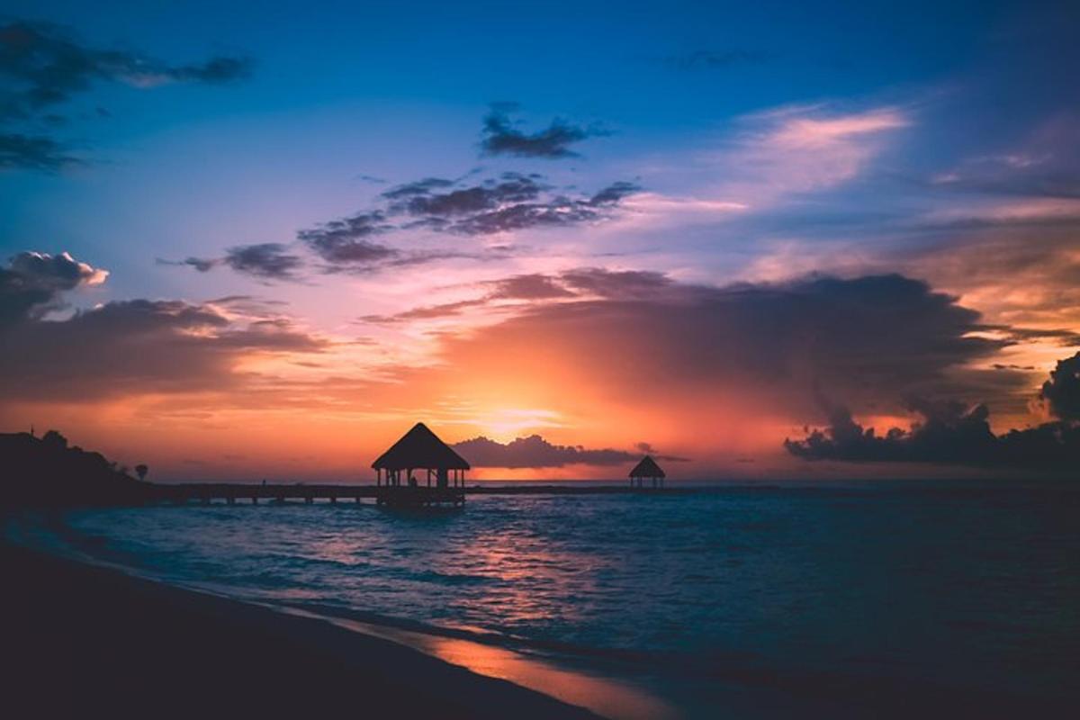 un tramonto su una spiaggia con un molo in acqua