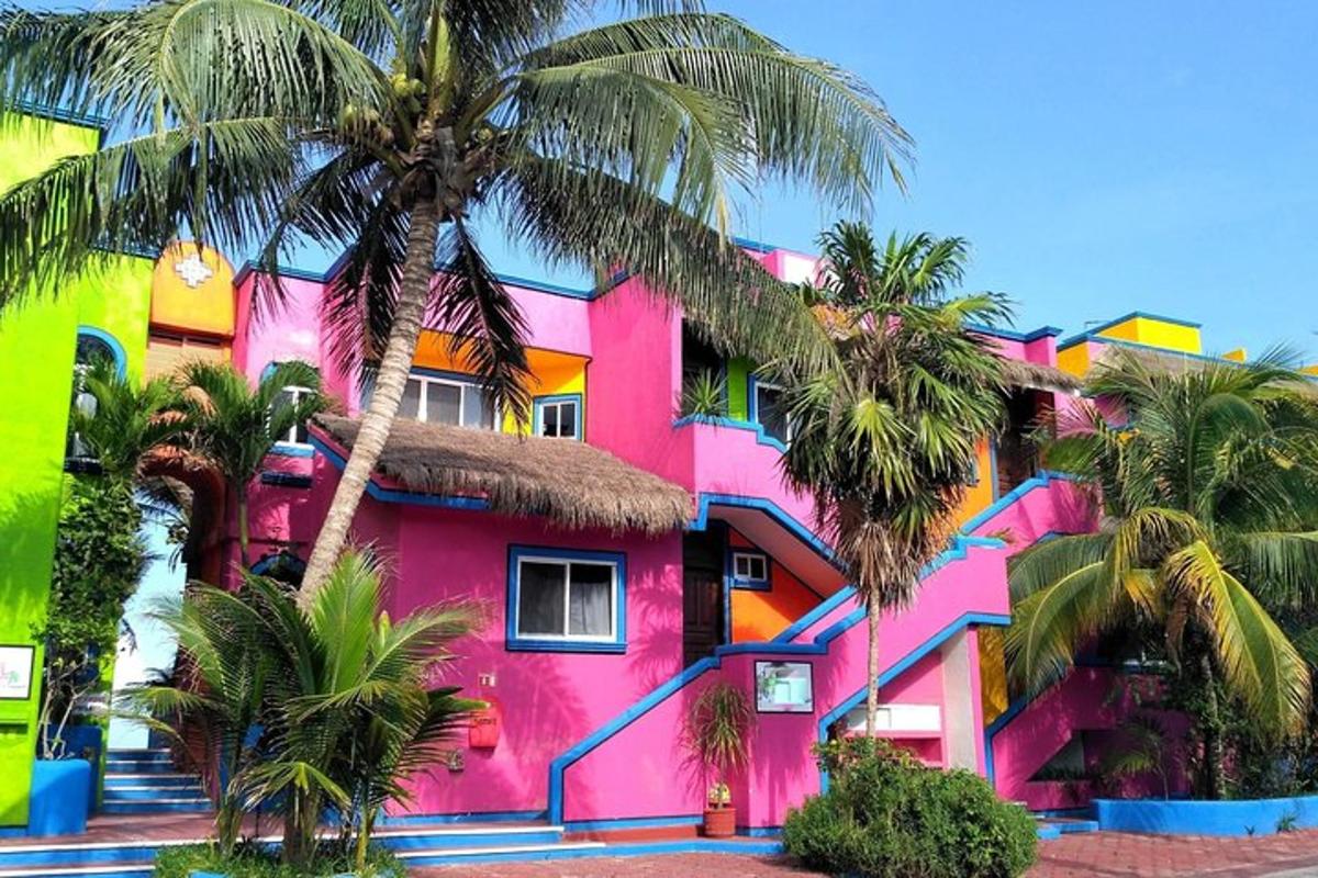 Un edificio rosa con palmeras delante.