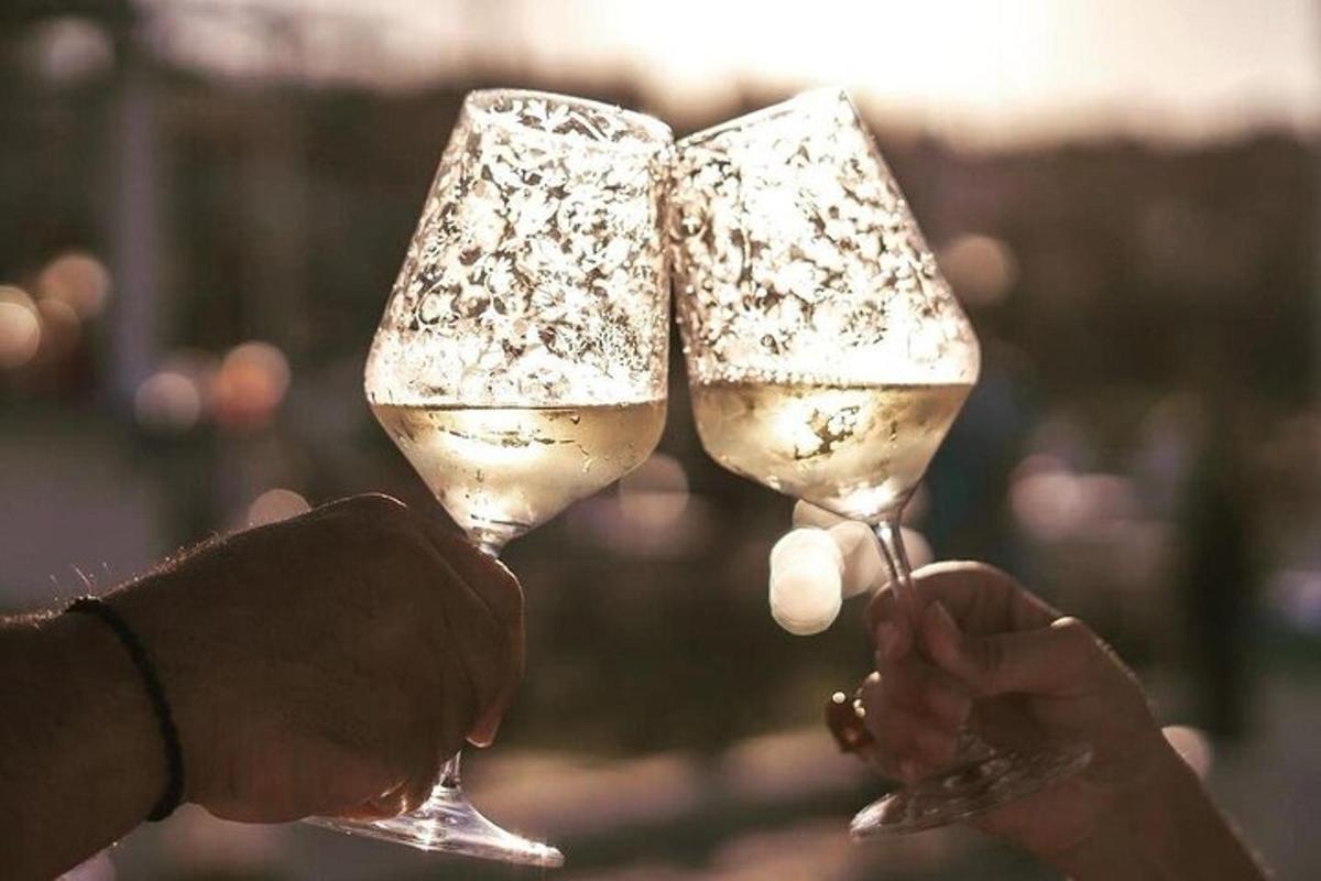 two people holding up glasses of white wine