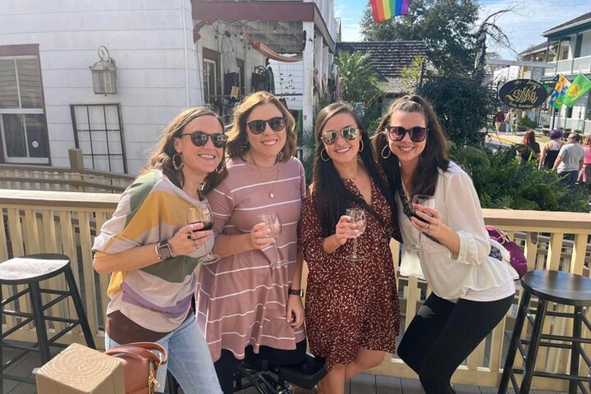 vier Frauen posieren für ein Foto und halten dabei Weingläser